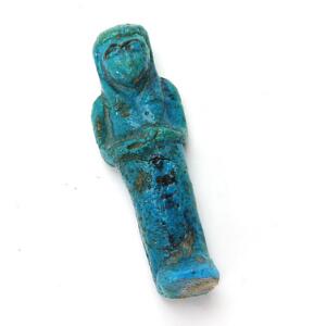 Ushabti af ægyptisk fajance, dekoreret i mørk turkis glasur. Antagelig 1. årt. f. Kr. H. 10,5 cm.