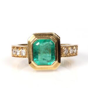 Smaragd-og diamantring af 18 kt. guld prydet med smaragdslebet smaragd flankeret af brillantslebne diamanter. Str. 54.