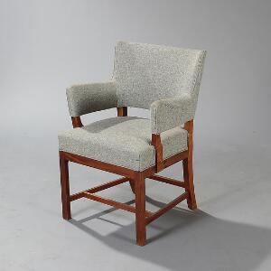 Tyge Hvass Armstol med stel af mahogni. Sider, sæde og ryg betrukket med grå uld. Udført hos snedkermester Jacob Kjær.