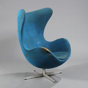 Arne Jacobsen Ægget. Skalformet hvilestol med profileret stamme og firpasfod, betrukket med blåt uld. Udført hos Fritz Hansen, 1965.