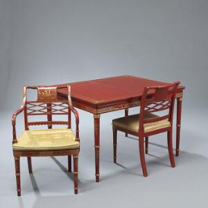 Spisestue af rødlakeret træ dekoreret i guld med kineserier, bestående af spisebord, seks stole og et par armstole samt to tillægsplader. Regency form. 20. årh.