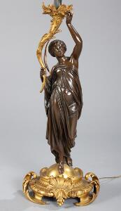 Standerlampe af delvis forgyldt og patineret bronze, støbt med kvinde i klassiske gevandter. 20. årh.s første halvdel. H. 170.