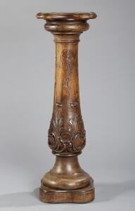 Piedestal af udskåret og poleret nøddetræ, rigt prydet med muslinger, bladværk, rocailler og kæmninger. Rococoform. 19. årh. H. 100.