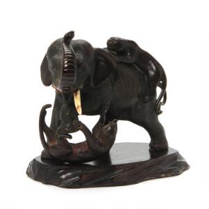 Japansk figurgruppe af bronze i form af elefant som bliver angrebet af to tigre, på base af træ. Sign. 20. årh. L. 22 cm.