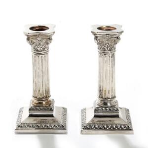 Et par stager af sølv, drevet med korinthiske kapitæler, kannelerede stammer på firkantede fodstykker. Mester F. Hingelberg. Udfyldte. H. 15. 2