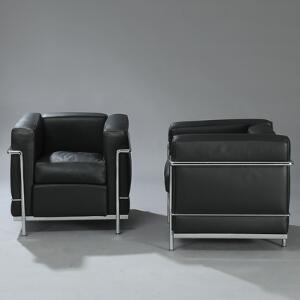 Le Corbusier LC 2. Et par lænestole med stel af forkromet stål, sæde, ryg, løse hynder og armlæn betrukket med sort skind. 2