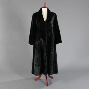 Lang swinger frakke af sort silkesæl, syet  med sjalskrave, hægtelukning og skrå indstiklommer. Str. ca. 44. Ca. 2000-2005.