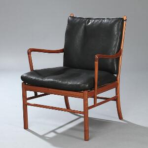 Ole Wanscher Colonial. Armstol af mahogni, sæde med spanskrørsflet. Løse hynder i sæde og ryg betrukket med sort skind. Model PJ-149.