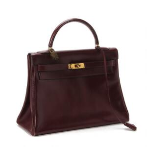 Hermés Kelly bag af bordeaux kalveskind med messing beslag og nøgle. L. 32 x 22 cm.