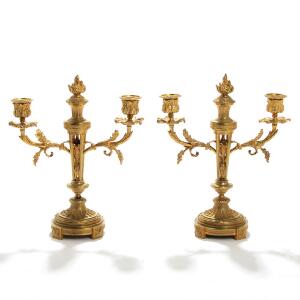 Et par franske kandelabre af forgyldt bronze med arme til to lys, runde fodstykker, gennembrudte stammer. 20. årh. H. 33. 2