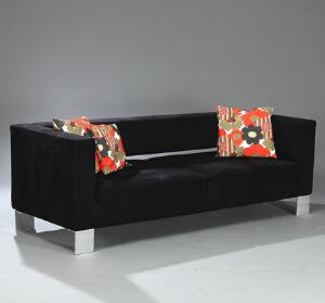 Fritstående tre-personers sofa betrukket med sort alkantara samt et par pufs betrukket med sort skind. 3