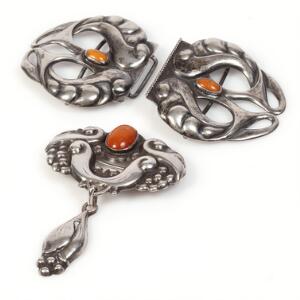 Broche og bæltespænde af sølv hver prydet med cabochonslebet rav. L. ca. 5 og 9 cm. Ca. 1950. 2