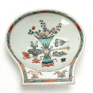 Famille verte tiggerskål af porcelæn i form af kammusling, dekoreret i farver med kostbare ting. Kangxi 1662-1722. L. 16 cm.