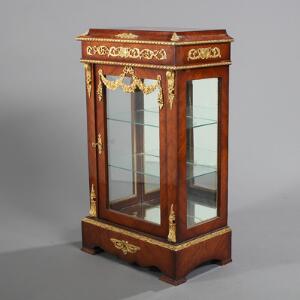 Vitrineskab af rosentræ, rigt prydet med monteringer af bronze, front og sider med glas. 20.-21. årh. H. 103. B. 62. D. 36.