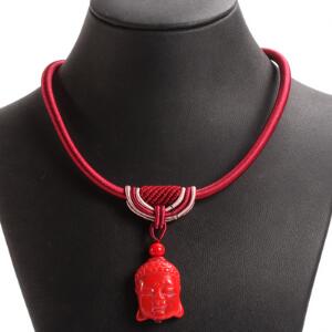 Halskæde af rød snor prydet med vedhæng i form af buddha hovede af rød agat. L. ca. 48 cm.