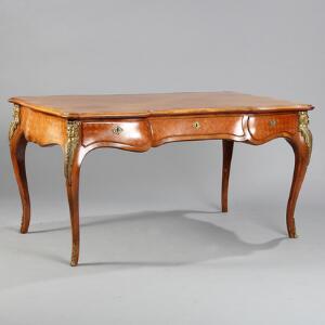 Fritstående skrivebord af rosentræ med indlægninger i lyst træ, prydet med beslag af bronze. Rococoform. H. 77. L. 151. B. 89.