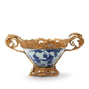 Skål af porcelæn i kinesisk stil, dekoreret i underglasur blå med personer i landskab med montering af forgyldt bronze. 20. årh. H. 23 cm.