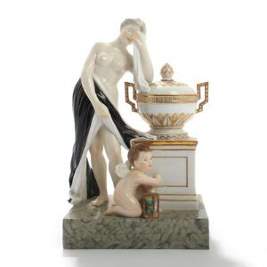 Kvinde og putti ved urne. Figurgruppe af porcelæn, Kgl. P., dekoreret i overglasurfarver. Juliane Marie mærke. H. 18,5.
