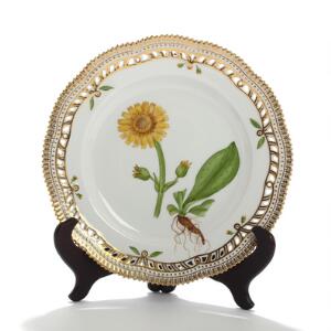 Flora Danica. Tallerken af porcelæn med gennembrudt fane, Kgl. P., dekoreret i farver og guld med blomster. Nr. 3553. Diam. 25,5.