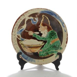 Paul Fischer Julegrøden. Rundt fad af brændt ler, dekoreret med nissefar ved julegrøden. Sign. Paul Fischer 88. Diam. 33.