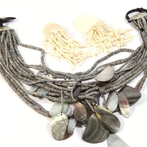 Gerda Lynggaard smykkesæt bestående af halsmykke med perler af kunstmateriale og vedhæng af perlemor samt lås af træ og hvide øreclips. ca. 12 og 46 cm.