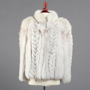 Kort jakke af polarræv syet i baner med kort krave og pelshægter. Str. ca. 40. L. midt bag 60. Udvendig ærmelængde L. 60. 2010.