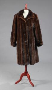 Frakke af brun Saga udrykket minkpels, syet med indstiklommer og pelshægter. Str. ca. 42-44. L. midt bag 104. Udvendig ærmelængde 65.