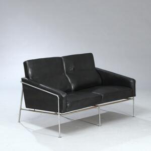 Arne Jacobsen Lufthavnssofa. Fritstående to-personers sofa på stel af forkromet stål. Sæde, sider og ryg betrukket med sort skind.