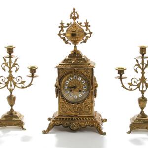 Urgarniture af bronze bestående af kaminur samt et par kandelabre, rigt støbt med løvehoveder og bladværk. 19. årh. H. 34-50. 3