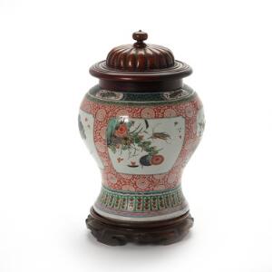 Kinesisk famille verte baluster vase i Kangxi maner, dekoreret i farver med blomster og fugle i firsidet felter. Låg af drejet træ. 19. årh. H. 22 cm. ex stand.