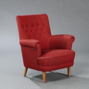 Carl Malmsten Lænestol opsat på tilspidsende ben af bøg. Sider, sæde samt dybthæftet ryg betrukket med rødnistret uld. Udført hos O. H. Sjögren, Sverige.