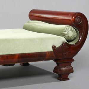 Skønvirke chaiselong af mahogni med hovedgærde i form af svanehals, sæde og løs pølle med grønt velour. Ca. 1900. L. 200. B. 90.