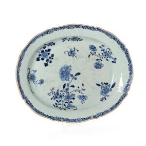 Kinesiskt dybt fad af porclæn med fliget fane, dekoreret i underglasur blå med blomster. Qianlong 1736-1795. L. 38,5 cm.