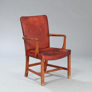 Kaare Klint Nørrevold. Højrygget armstol af teak. Sæde og ryg betrukket med messingsømbeslået, patineret rødbrunt skind. Model 5999.