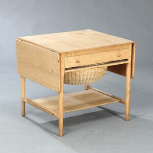 Hans J. Wegner AT 33. Sybord af massiv eg med klapper, front med skuffe hvorunder kurv af flet samt underliggende hylde.