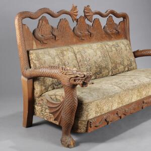 Sofa af nøddebejdset træ, rigt udskåret med drager i kinesisk stil. Ca. 1930. L. 185.