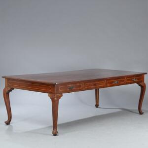Stort skrivebord af mahogni, indlagt med lister af lyst og mørkt træ, sarg med otte skuffer, svungne ben. 19. årh.s slutning. H. 80. L. 238. B. 127.