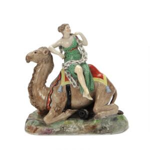 Asien - figur af porcelæn, dekoreret i overglasurfarver, i form af siddende kvinde på liggende dromedar. Kgl. P. 18. årh.s slutning. H. 19 cm.