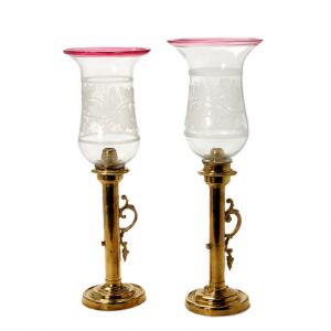 To hurricane stager af messing med to forskellige shades af glas med rosa kant og slebet dekoration. 19.-20. årh. H. 46-48 cm. 2