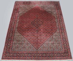 Orientalsk tæppe i klassisk Bidjar design med kantet hagemedaljon på rød bund med heratimønste. God fast kvalitet. Ca. år 2000. 344 x 247.
