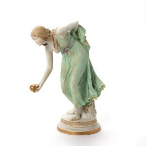 Jugend figur af bemalt bisquit i form af kvinde i klassiske gevandter som spiller boccia. Ca. 1900. H. 31 cm.