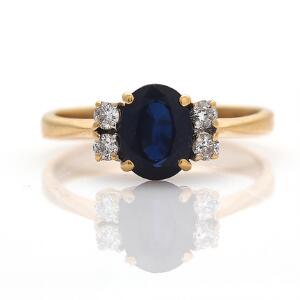 Safir- og diamantring af 18 kt. guld prydet med facetslebet safir flankeret af brillantslebne diamanter. Str. 56.