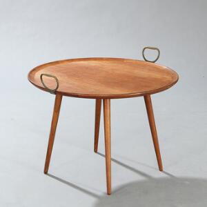 Dansk møbeldesign Sofabord af massiv teak, opsat på tilspidsende ben. Cirkulær top med greb af messing. Udført for Illums Bolighus, med plakette herfra.