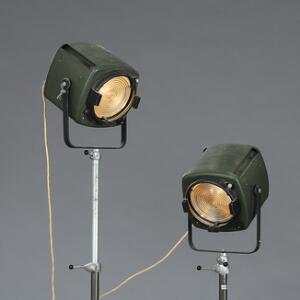 Et par teaterprojektører af stål, med grønmalede lampehoveder, regulérbare stammer samt greb og fødder af bakelit. Strand Electric, England. Ca. 1960. H. 170.