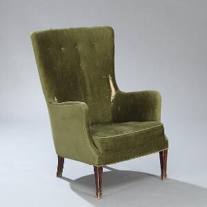 Frits Henningsen Højrygget lænestol opsat på tilspidsende, profilerede ben af mahogni. Sider, sæde og ryg betrukket med grøn plys.