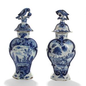 To Delft lågvaser af fajance, dekorerede med landskaber og figurer i blå, lågknopper i form af fugl. Sign. monogram. H. 37. 2