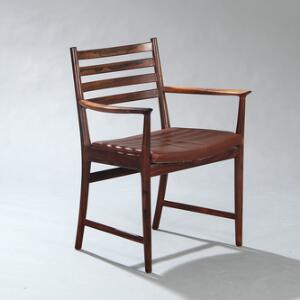 Kaj Lyngfeldt Larsen Armstol af palisander med fire horisontale sprosser i ryg. Sæde betrukket med brunt farvet skind. Udført hos Søren Willadsen.