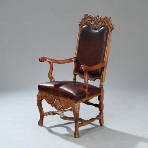 Højrygget dansk regence armstol af bøgetræ, med gennembrudte armlæn og ryg og sæde betrukket med brunt skind. 18. årh.s første halvdel.