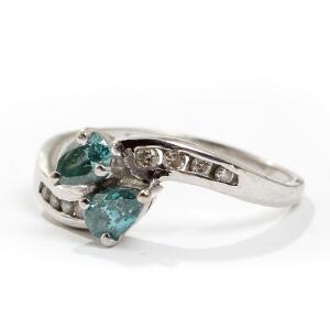 Diamantring af 14 kt. hvidguld, prydet med to dråbeslebne fancy blå diamanter, flankeret af talrige brillantslebne hvide diamanter. Str. 57,5.