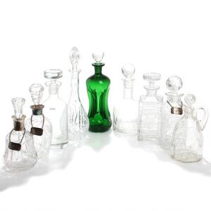 Klukflaske af grønt glas samt otte karafler af glas og krystalglas, to monteret med krave af sølv, tre vinskilte af sølv. 20. årh. H. 23-32. 9
